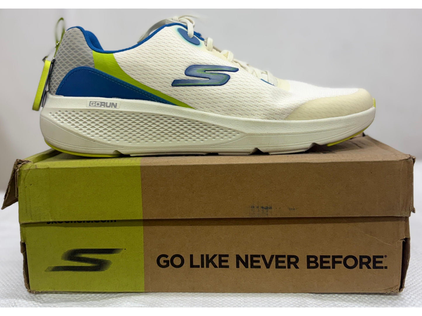Side view of an off-white Skechers GORUN running shoe with royal blue and lime green accents on a Skechers shoe box