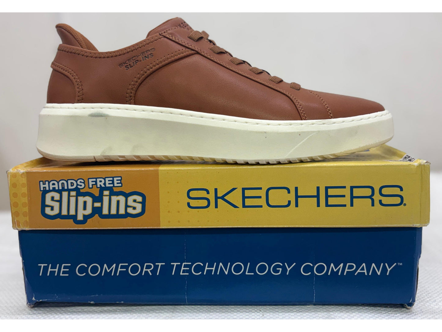 Tan Skechers Hands Free Slip-ins casual shoe with cream sole on yellow and blue Slip-ins box.