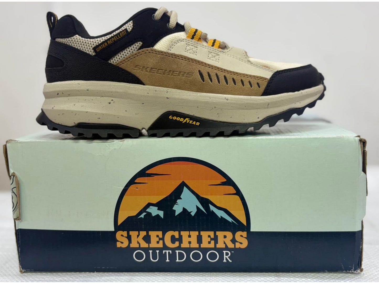 Tan and black Skechers Outdoor trail shoe with Goodyear outsole and water-repellent tag on Outdoor box.