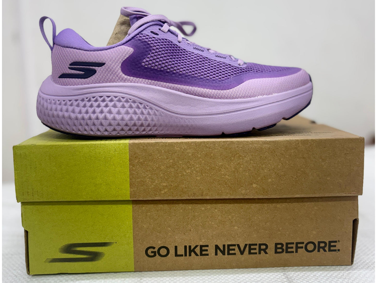 Purple Skechers GO WALK performance walking shoe with thick lavender midsole on GO-branded box.