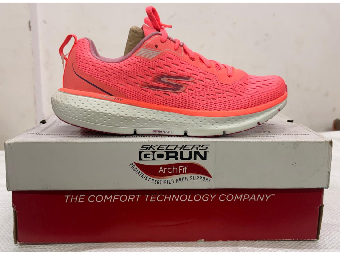 Bright coral Skechers GORUN Arch Fit running shoe with white Ultra Flight midsole on branded shoebox.