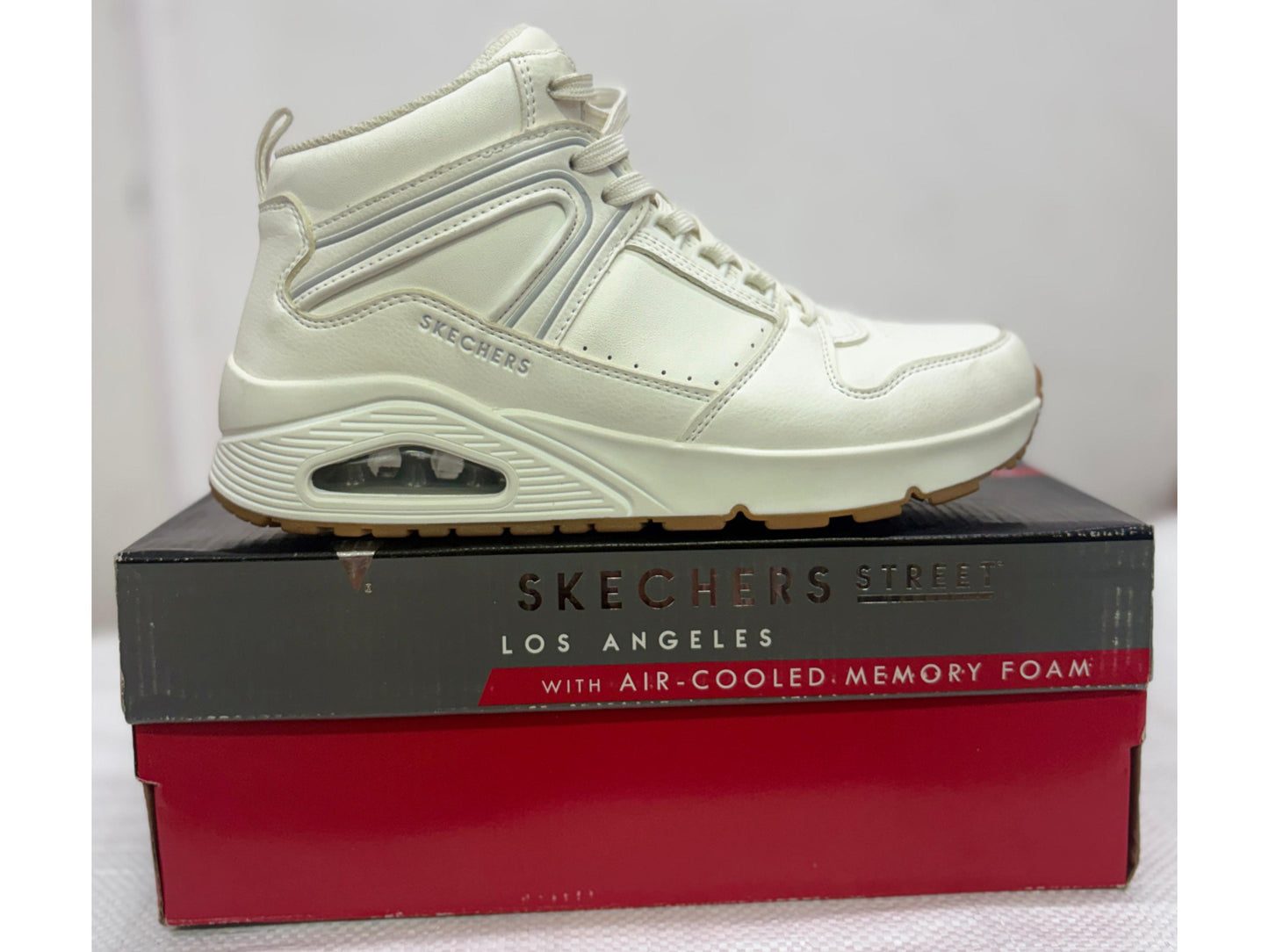 Side view of an off-white Skechers Street Uno mid-top sneaker with visible air-cushioned heel and gum sole