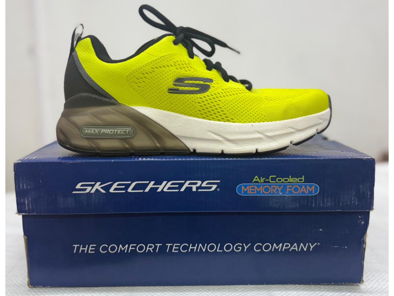 Side view of a neon yellow Skechers Max Protect shoe with translucent grey heel unit and white forefoot midsole
