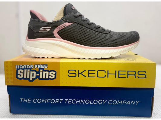Charcoal grey Skechers Hands Free Slip-ins walking shoe with pink accents and cream sole on yellow Slip-ins box.