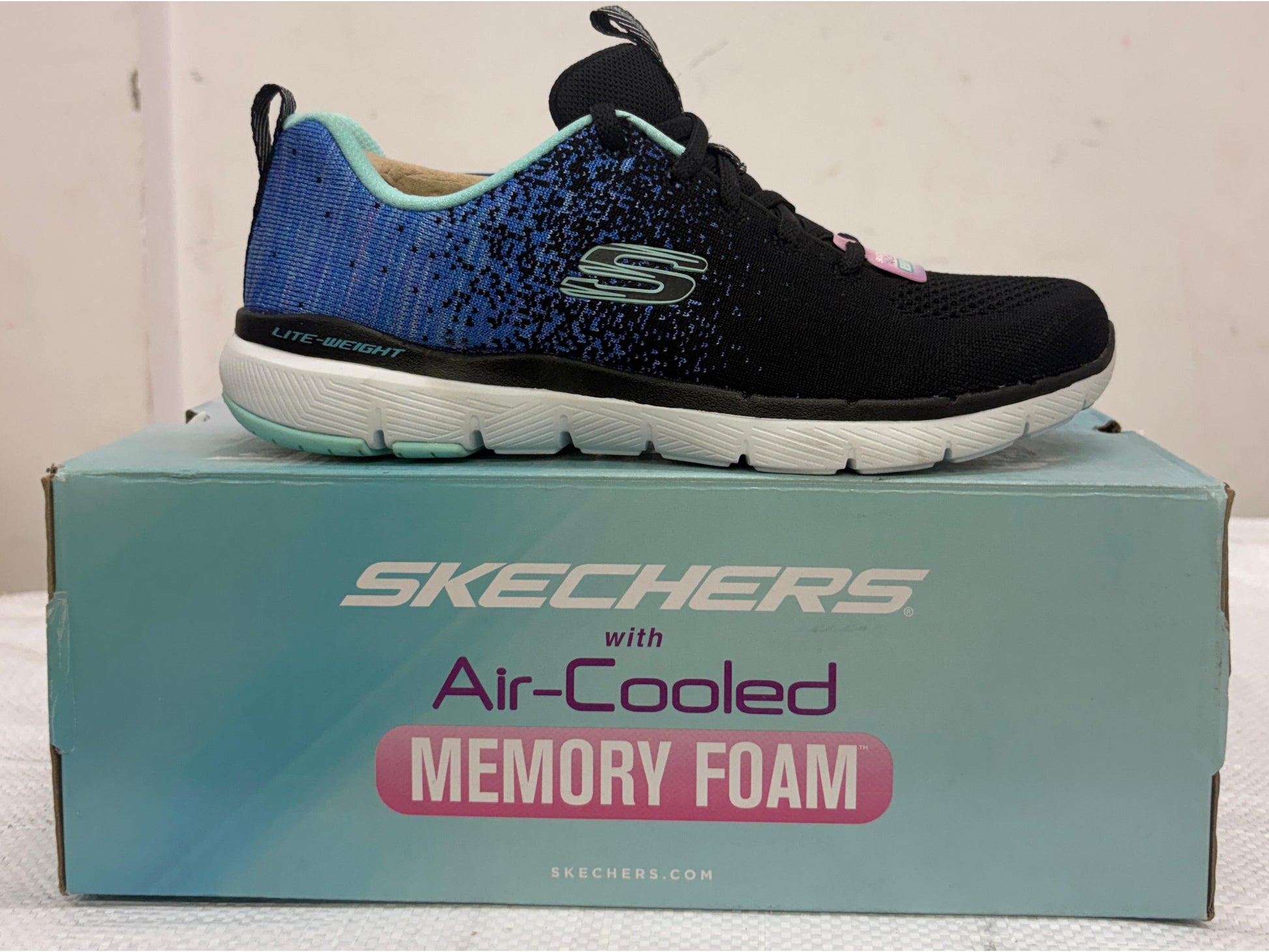 Black and blue gradient Skechers Lite-Weight walking shoe with teal accents on Air-Cooled Memory Foam box.