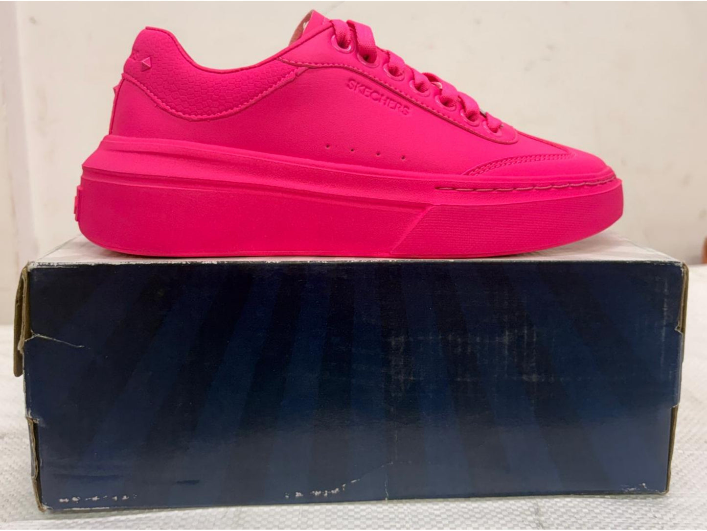 Monochromatic hot pink Skechers platform sneaker with chunky sole on blue shoebox.